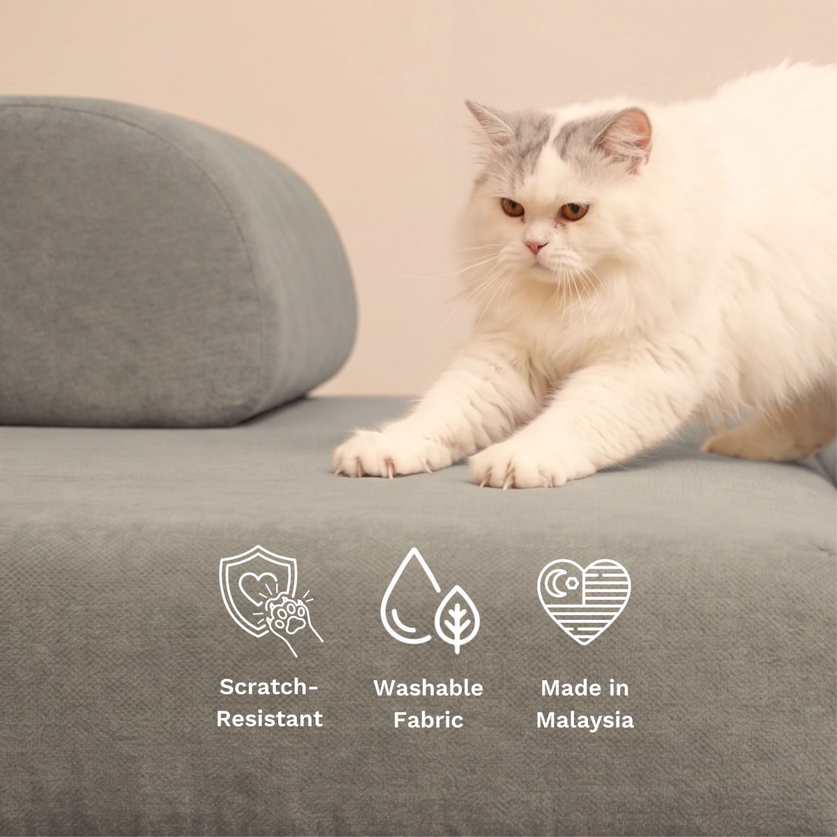 A fluffy white and gray cat lies on a gray upholstered Sonno sofa cushion with a matching round cushion behind it. White line icons and text at the bottom read 'Scratch-Resistant', 'Washable Fabric', and 'Made in Malaysia'.