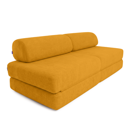 A mustard yellow Sonno sofa bed with a cylindrical lumbar pillow, shown from a three-quarters angle on a white background.