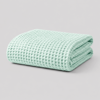 Folded mint green Sonno waffle-textured bamboo blanket on a light grey background