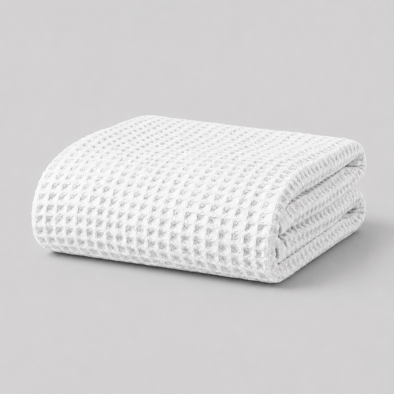 Folded white textured Sonno waffle blanket bamboo on a grey background