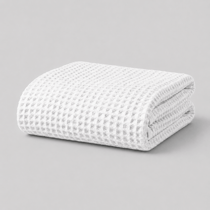 Folded white textured Sonno waffle blanket bamboo on a grey background