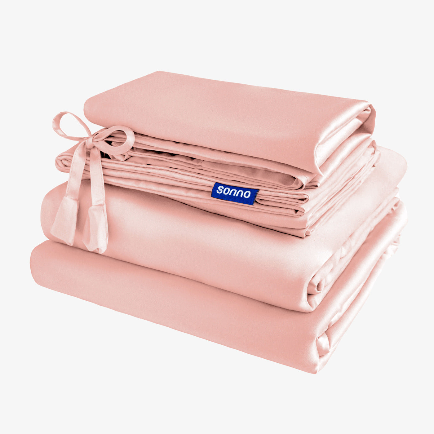 Sonno pink bedding set showcasing a stack of silky sheets and pillowcases, elegantly tied with a ribbon. The soft, pastel color is displayed against a light background, emphasizing comfort and style in bedroom decor. The Sonno logo is prominently featured.