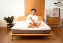 Man sitting on Sonno Original mattress in a Japandi bedroom